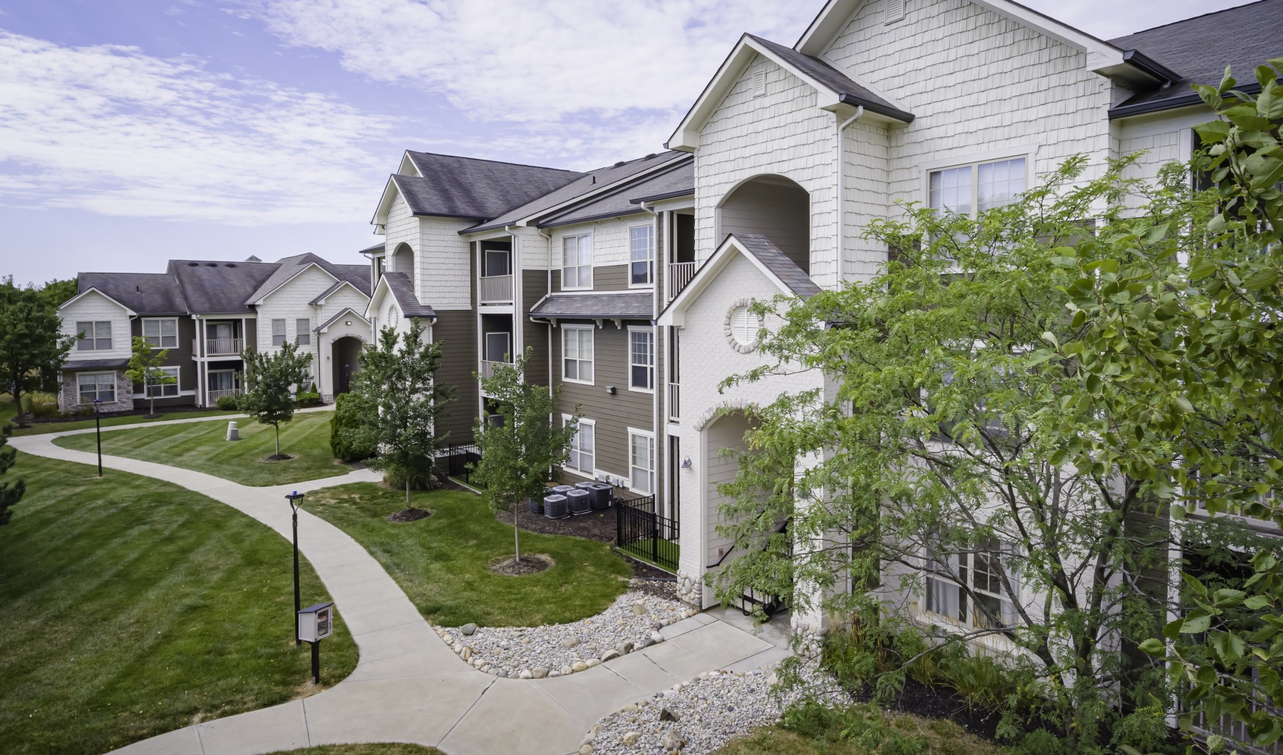 Find your apartment at Prairie Lakes in Noblesville Apartment building exterior with trees and walking paths